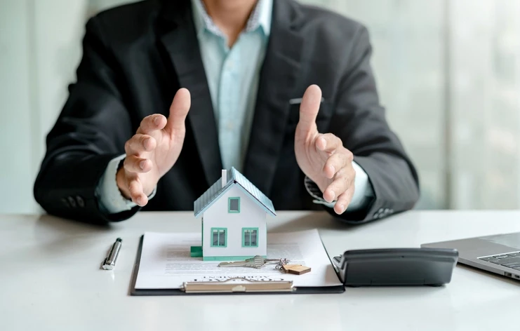 Une personne couvrant une maquette de bien immobilier avec ses mains, l'image d'un chargé de gestion locative auquel est confié la gestion d'un bien en location.