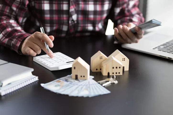 Un investisseur immobilier entrain d'utiliser une machine à calculer au bureau, une étape importance pour maîtriser la gestion locative tarif.