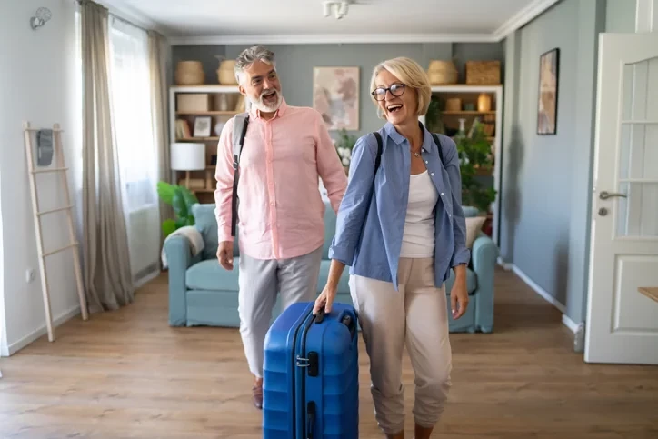 Deux couples heureux avec des bagages, entrain d'arriver dans un logement soumis à un mandat de gestion locative airbnb, gage d'un service de qualité.