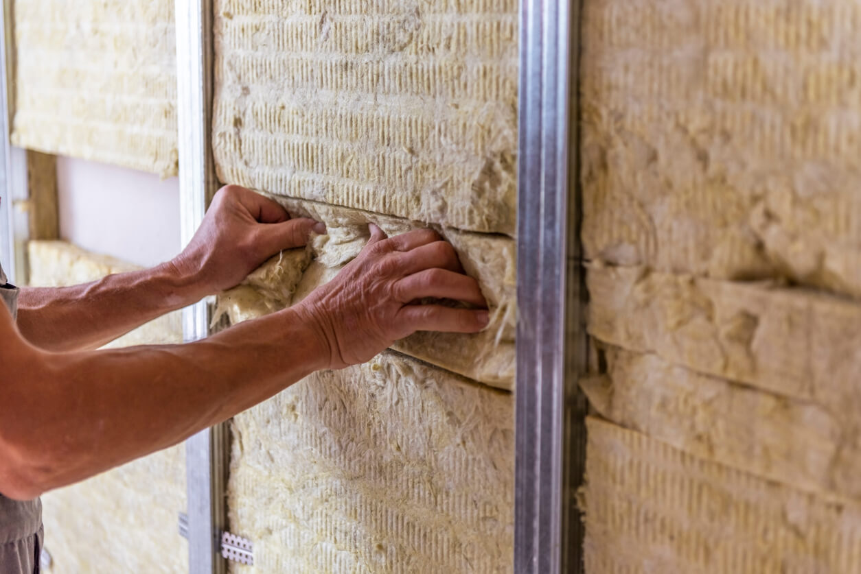 L'artisan est en train de mener à bien les travaux rénovation énergétique en réalisant l'isolation des murs.