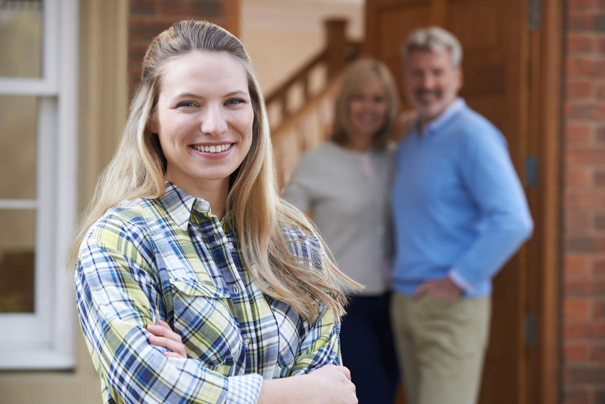 Une famille heureuse pose devant leur maison, acquise grâce à une SCI, illustrant les avantages de ce mode d'acquisition pour protéger et transmettre leur patrimoine immobilier.