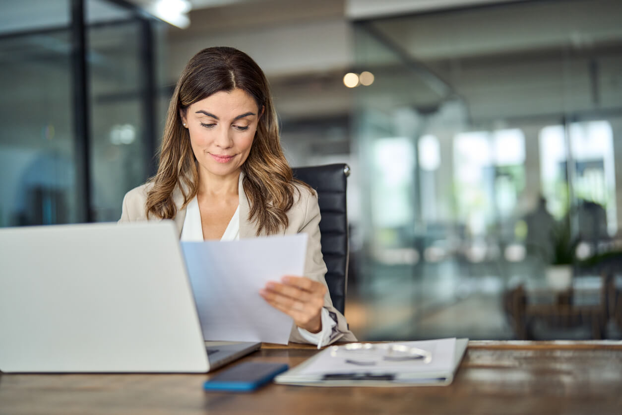 Une femme examinant des documents liés à la création d'une SCI, réfléchissant au capital minimum nécessaire pour assurer une gestion optimale et solide.