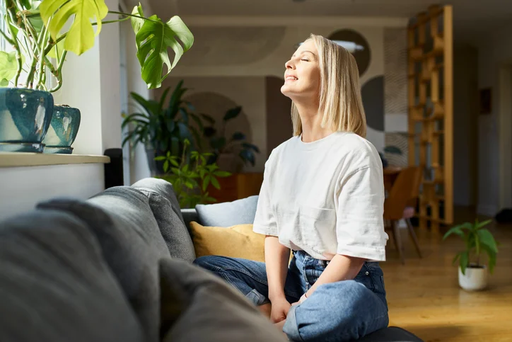 Une femme heureuse assise sur un canapé, montrant la tranquillité d'esprit des propriétaires en faisant appel à une agence gestion location