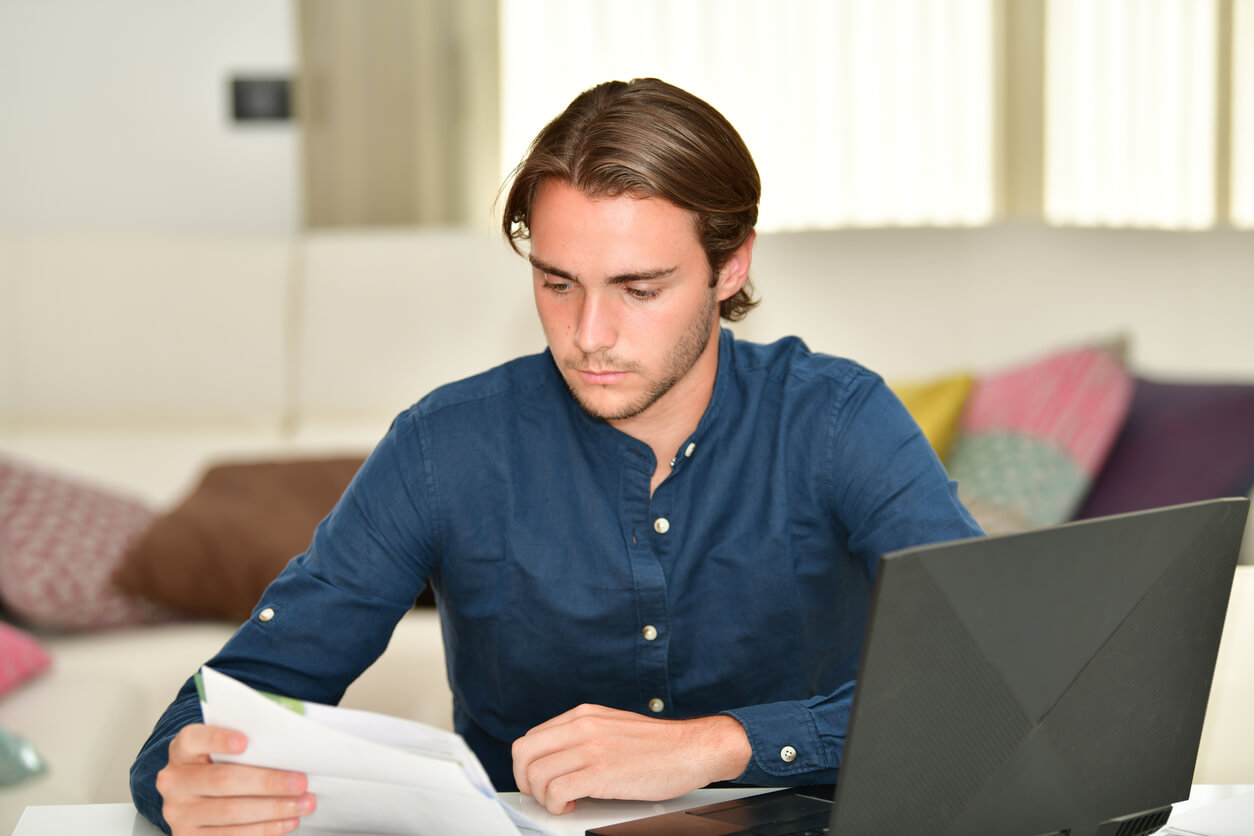 Un homme au bureau examine des documents liés à un investissement immobilier, réfléchissant à ses options de défiscalisation immobilière pour optimiser ses avantages fiscaux.