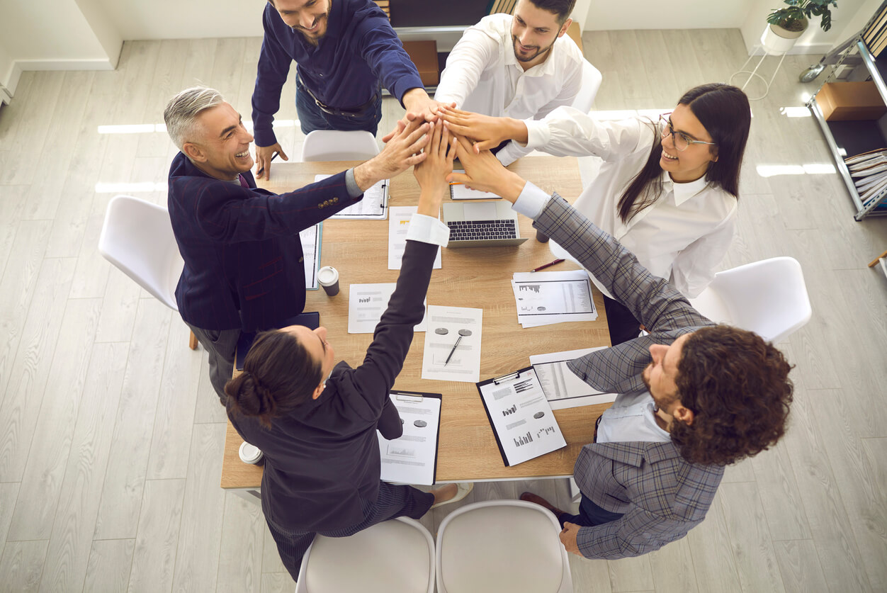 L'image montre une réunion entre collaborateurs autour d'une table en train de sourire et semble-t-il de s'accorder sur une décision symbolisant dans l'article une bonne entente entre les associés d'une SCI lors d'une AG