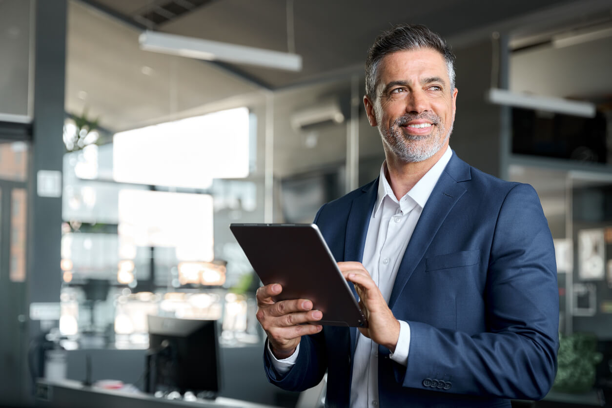 Un investisseur souriant avec une tablette à la main, symbolisant le succès de la gestion immobilière optimisée grâce à une SCI.