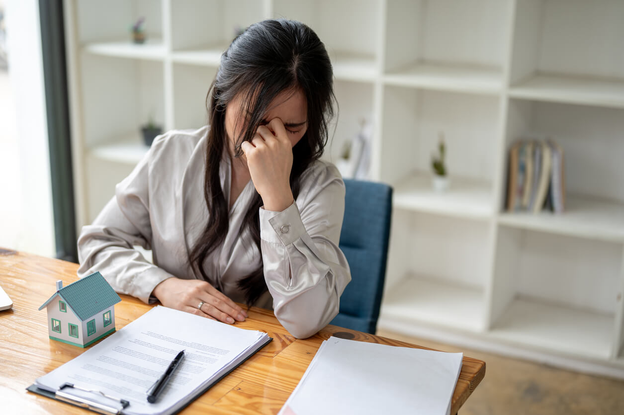 Image d'une femme au bureau avec des dossiers, illustrant les erreurs à éviter lors d'un emprunt SCI, telles que la sous-estimation de la capacité d'emprunt ou la négligence des coûts annexes.