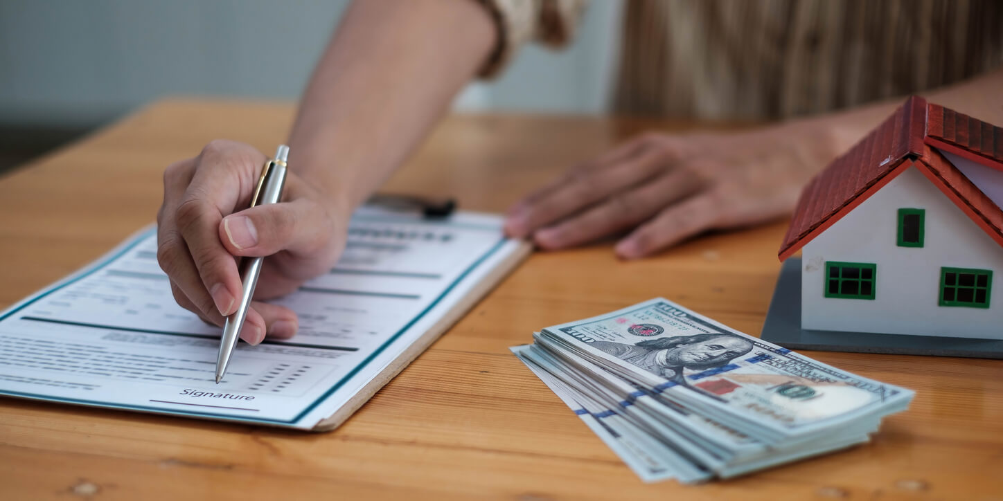 Une personne examine des documents et remplit un formulaire pour finaliser les démarches nécessaires à l'obtention d'un prêt immobilier SCI.