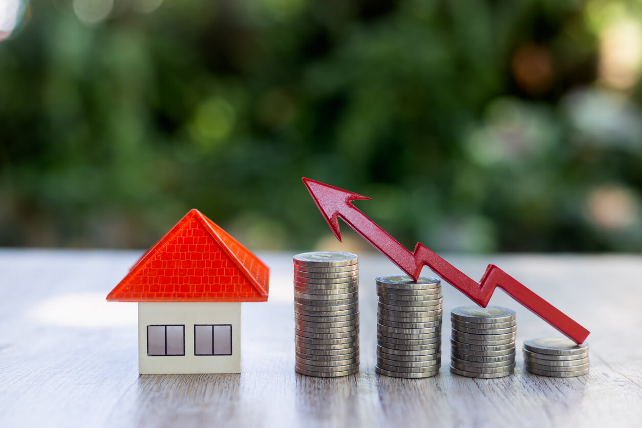 Image d'une petite maison, avec une pile de pièces de monaies et une flèche rouge pour représenter le mot clé: amortir son bien immobilier en lmnp