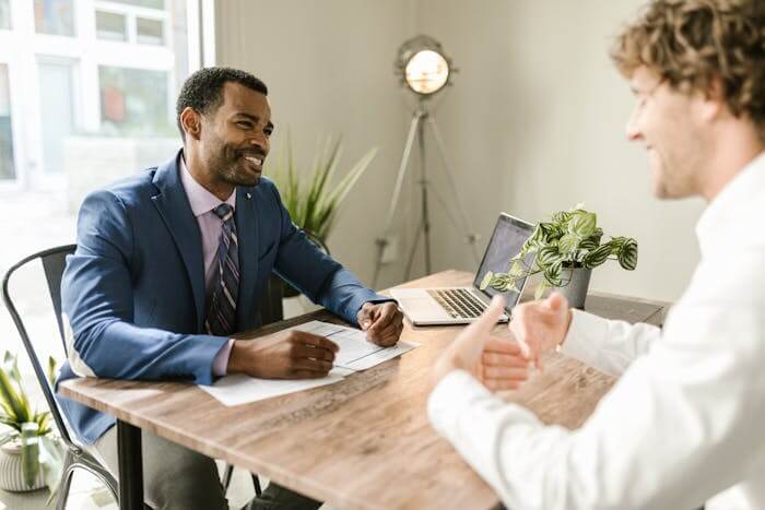 Un investisseur immobilier échange avec un comptable dans un bureau moderne, discutant de la gestion de la comptabilité pour son investissement en Loueur Meublé Non Professionnel (LMNP).