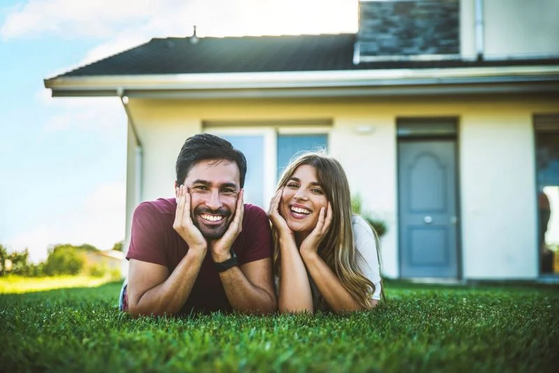 Un couple heureux sur une pelouse, devant leur location appartement à Annecy