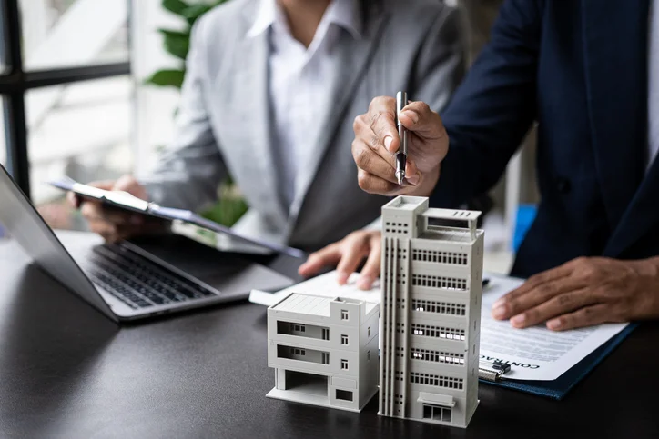 Deux employés de bureau d'une agence gestion location, ayant devant eux des maquettes de bien immobilier à gérer