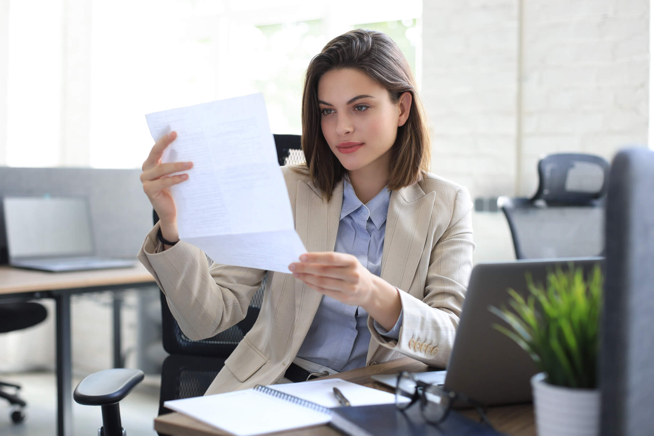 Une femme examine attentivement des documents de financement, analysant les options disponibles pour le rachat de parts sociales entre associés, en vue de finaliser l'accord et ajuster la répartition du capital de l'entreprise.