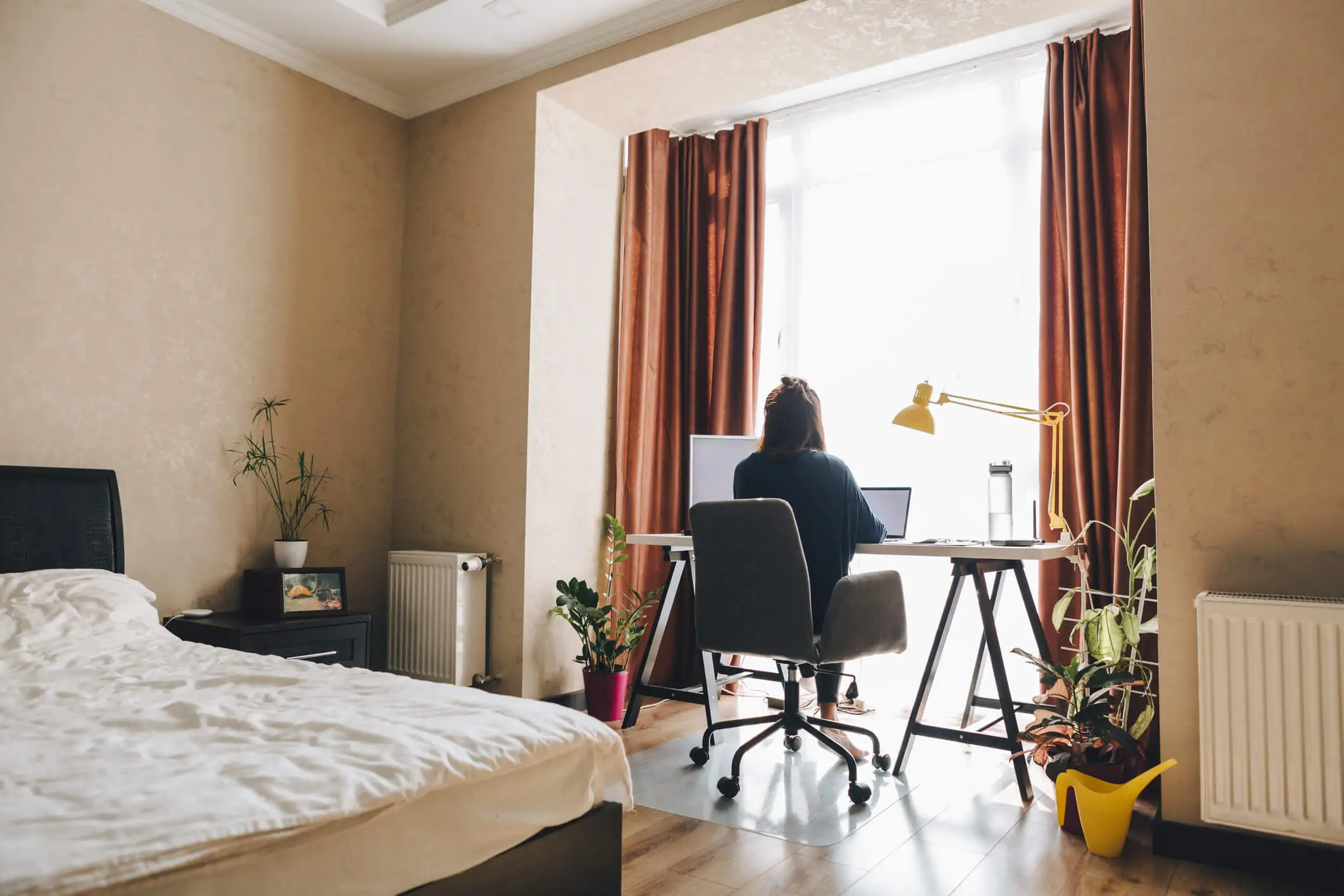 Une étudiante installée dans son studio meublé, concentrée sur son ordinateur. Son espace optimisé comprend un lit, un bureau et une kitchenette moderne. Ce type de logement, prisé par les jeunes en formation, illustre l’intérêt d’acheter une résidence étudiante pour investir dans un bien offrant rentabilité et sécurité locative.