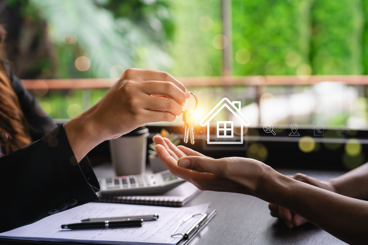 Un propriétaire de SCI remet les clés d’un bien immobilier à un acheteur, avec des documents juridiques sur la table. Cette transaction symbolise la cession d'un bien, où la plus-value immobilière doit être déclarée et optimisée pour réduire l'imposition fiscale.